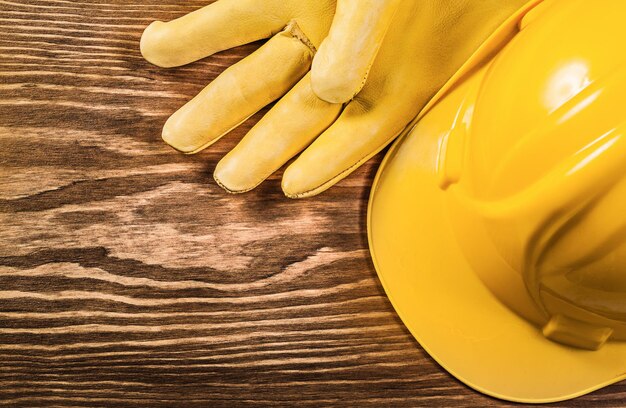 Yellow protective gloves building helmet on wooden board construction concept