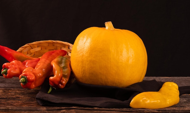 Yellow pumpkin and long peppers on a wooden old table space for text