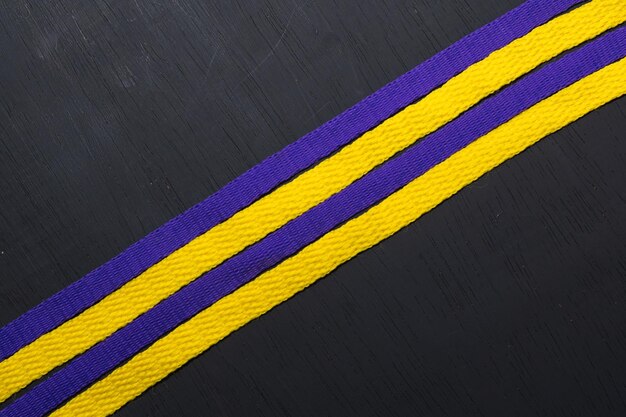 Yellow and purple shoelaces lakers flag on black wooden background