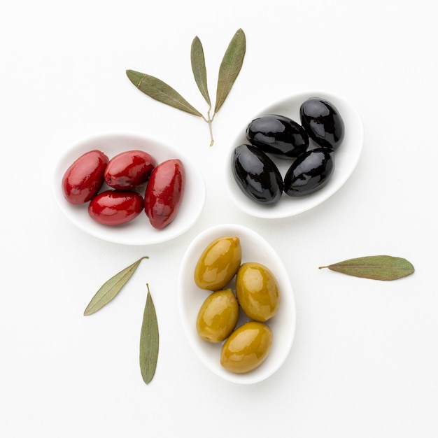 Olive nere rosse gialle sui piatti con le foglie