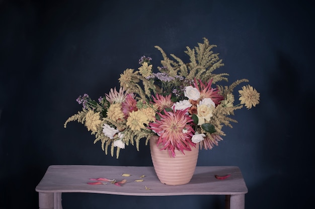 Photo yellow and red flowers in vase on vintage shelf