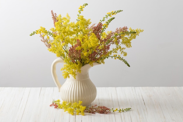 Yellow and red flowers in vase on wooden table