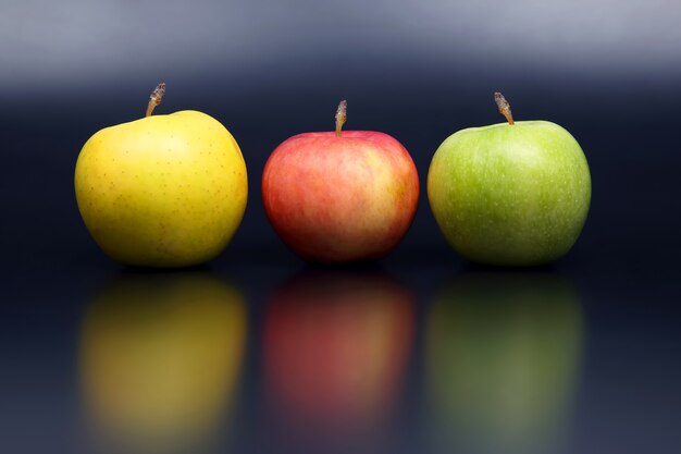 Photo yellow, red and green apples on dark space