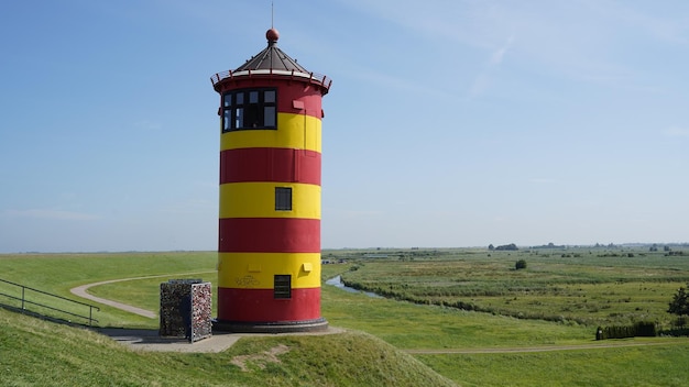 Yellow and red lighthouse on field against sky