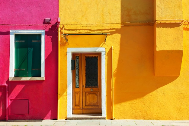 Facciata della casa dipinta di giallo e rosso. edifici colorati a burano, venezia, italy