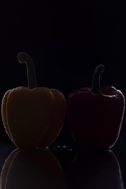 Photo yellow and red peppers on a black background closeup of vegetables with drops