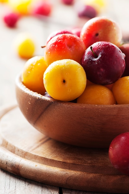 Yellow and red sweet plums on the wooden table