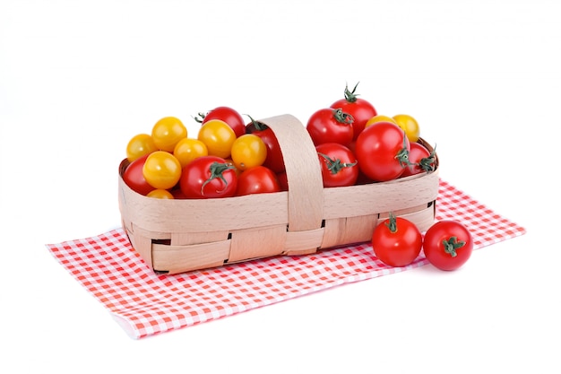 Yellow and red tomatoes lie in basket on a white surface