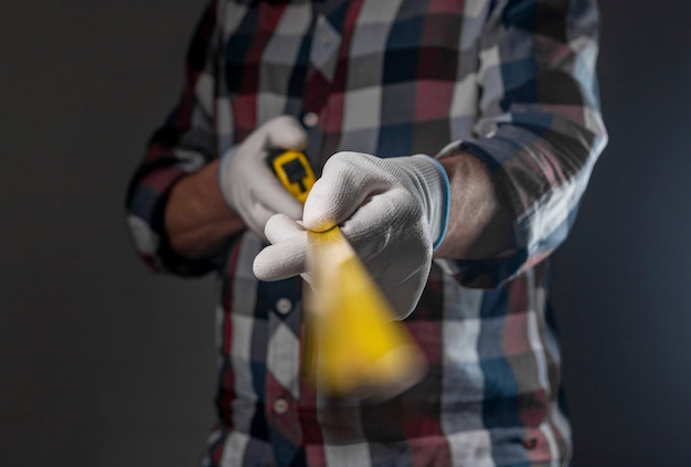 Yellow retractable tape measure tool in hands of repairman closeup