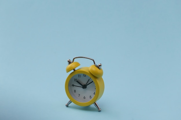 Yellow retro alarm clock on blue background.