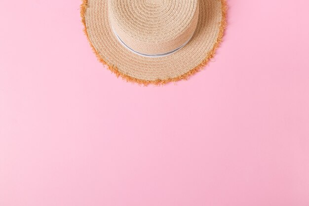 Yellow retro straw hat top view with copy space. summer concept on pink background.