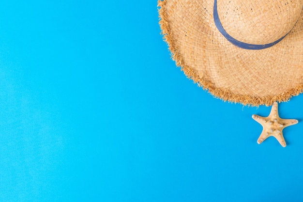 Yellow retro straw hat with seastar top view with copy space. summer concept on blue background.