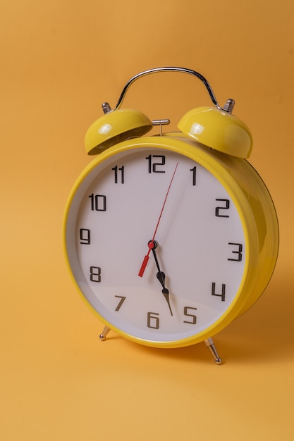 Yellow Retro style alarm clock over yellow background.