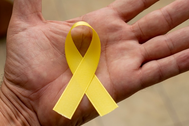 Photo yellow ribbon on the palm. september yellow. suicide prevention campaign