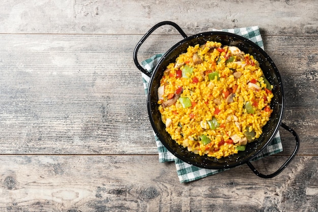 Foto riso giallo con pollo e verdure su un tavolo di legno