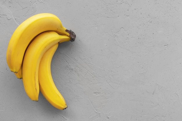 Yellow ripe bananas on concrete gray background, top view, copy space