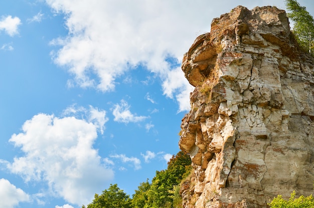 Yellow rock on blue sky with clouds.                               