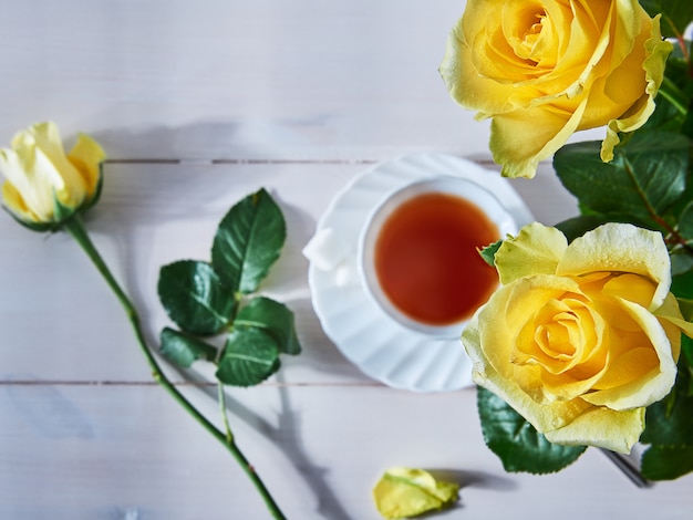 Photo yellow roses and a cup of hot drink
