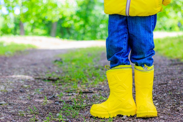 Yellow rubber boots on the child's feet in the park