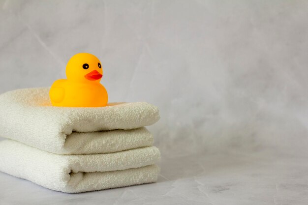 A yellow rubber duck for bathing on a stack of clean white towels