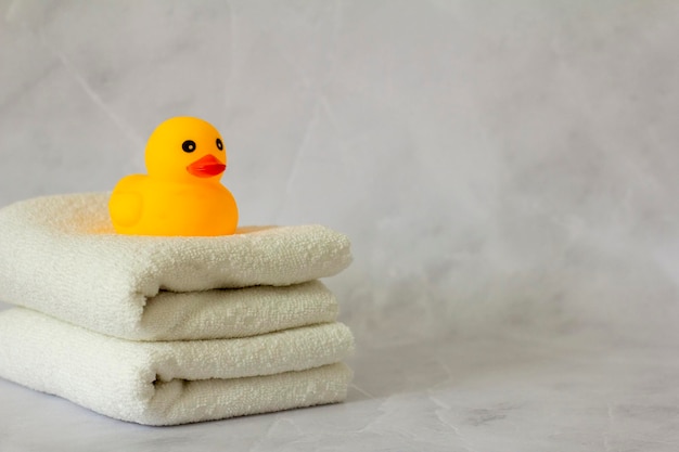 A yellow rubber duck for bathing on a stack of clean white towels
