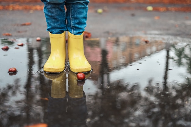 写真 雨が降った後、水たまりに黄色いゴム靴。落ち葉。秋のシーズンのコンセプト。