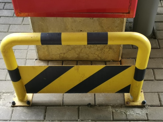 Yellow safety barrier with black stripes put outside by the stone pillar