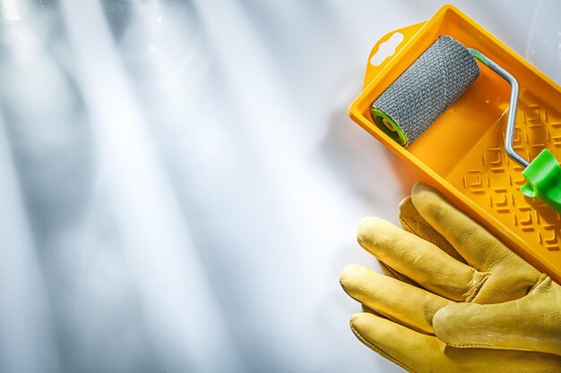 Yellow safety gloves paint tray roller on white background