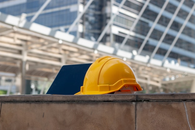 Photo yellow safety hat with laptop computer on the floor