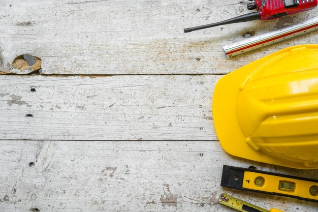 yellow safety helmet and rolled up architectural blueprints on a wooden desk