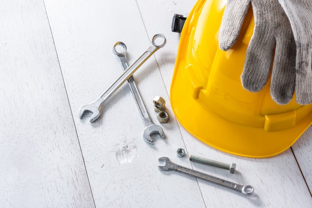 Yellow safety helmet and tools on white wooden table