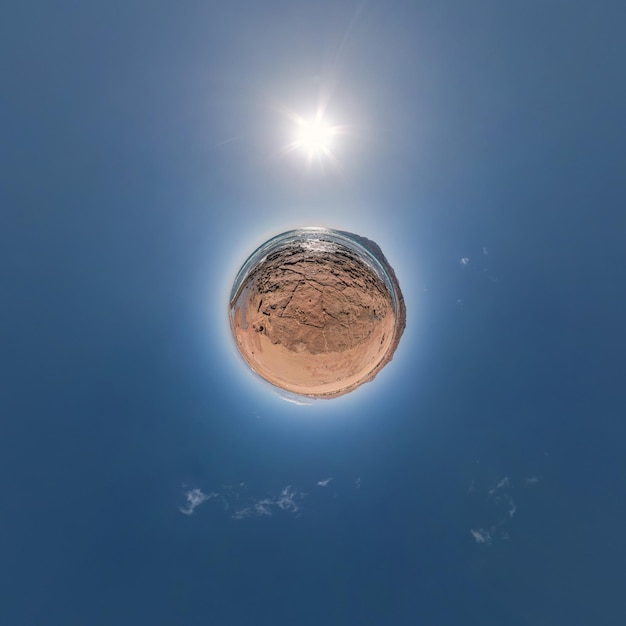 Yellow sand tiny planet in blue sky with beautiful clouds\
transformation of spherical panorama 360 degrees spherical abstract\
aerial view curvature of space