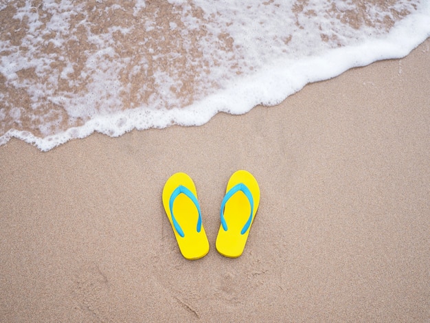 Photo yellow sandal on beige sand summer beach