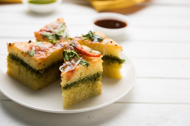 Yellow Sandwich Dhokla is een Indiase hartige snack gemaakt van kikkererwtenmeel of rijstmeel, afkomstig uit Gujarat. Geserveerd met groene en tamarindechutney. selectieve focus