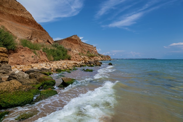 Photo yellow sandy rocks and stones of various forms on the black sea coast. blue sky and turquoise water.