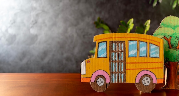 Yellow school bus made of cardboard and plants arranged on students' desks Blackboard background back to school concept There is empty space