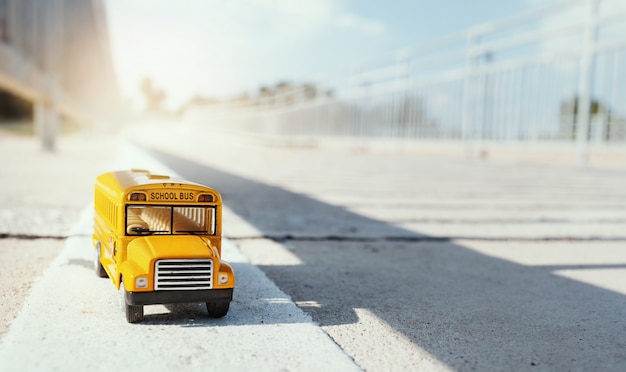 Yellow school bus toy model on country road.Back to school concept background.