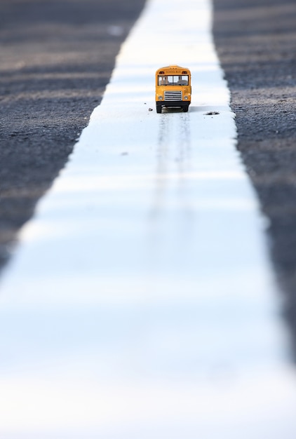 Yellow school bus toy model on country road .Shallow depth of field composition.