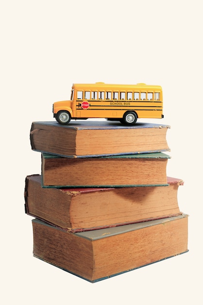 Yellow school bus toy model and old books.Vintage background.