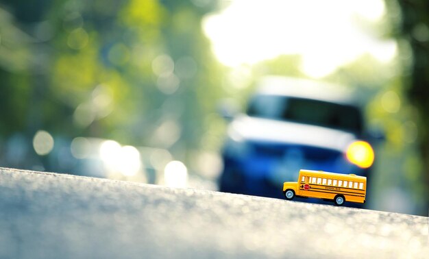 Yellow school bus toy model the road crossingShallow depth of field composition and afternoon scene