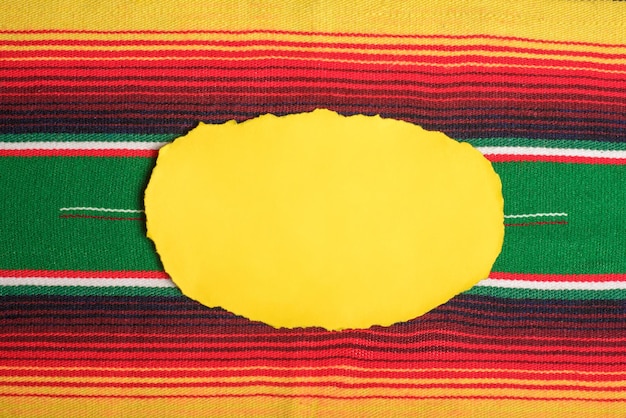 Photo yellow scrap paper on colorful serape empty template for text cinco de mayo background