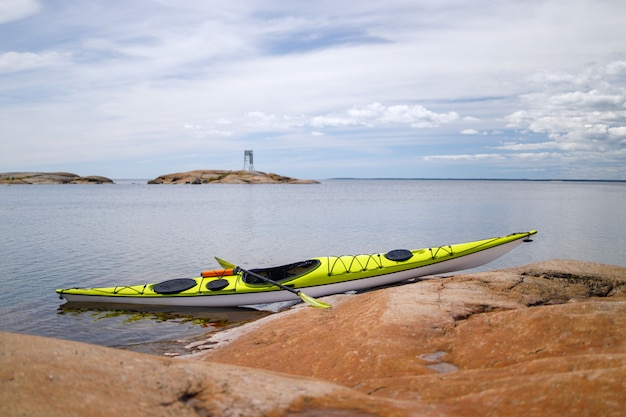 Yellow sea kayak on the granite shore in focus. background is blurred.