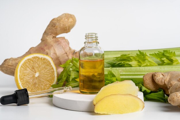 Photo yellow serum or oil ginger extract in droppper bottle on white podium vegetables around