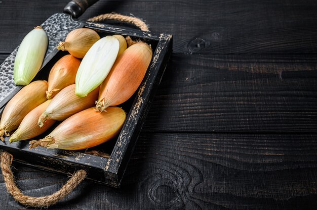 Yellow shallot onions, cut in two halves in a wooden box.