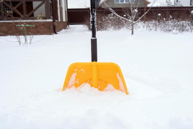 雪の中に立っている黄色いシャベル