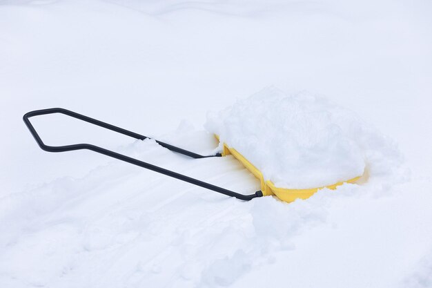 A yellow shovel with snow is lying in a snowdrift Cleaning tool Selective focus