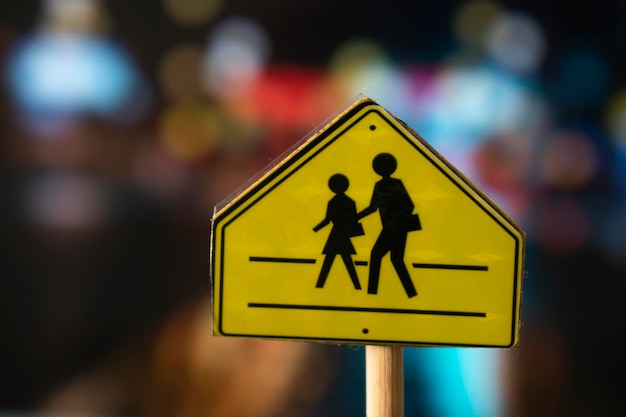 A yellow sign with a picture of a child and a person walking across it.