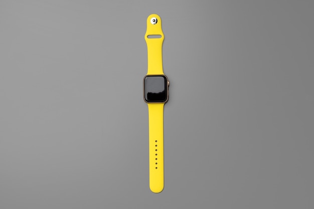 Yellow smartwatch on gray background close up