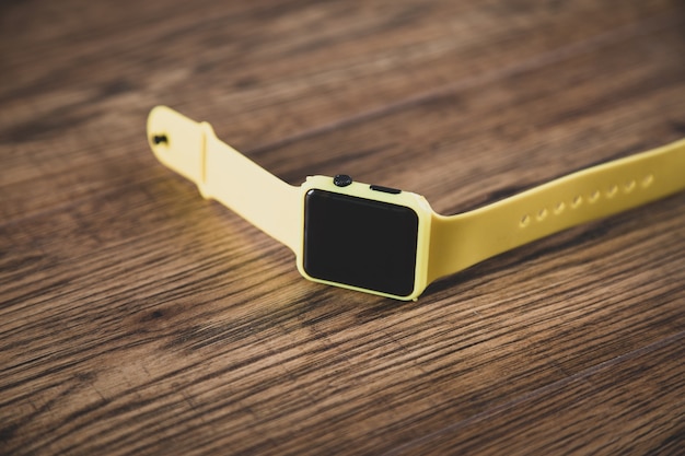 나무 테이블에 노란색 smartwatch