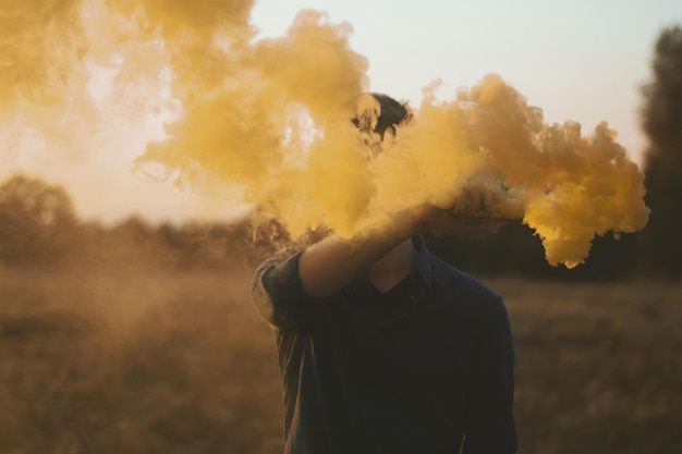 Foto fumo giallo emesso da una torcia di soccorso tenuta da un giovane